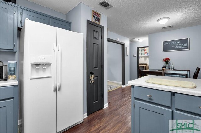 kitchen with visible vents, white fridge with ice dispenser, dark wood finished floors, and light countertops