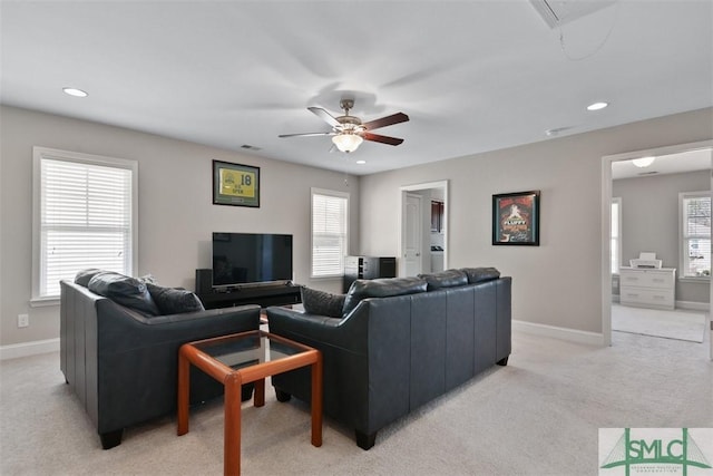 living area featuring a wealth of natural light, light colored carpet, and baseboards