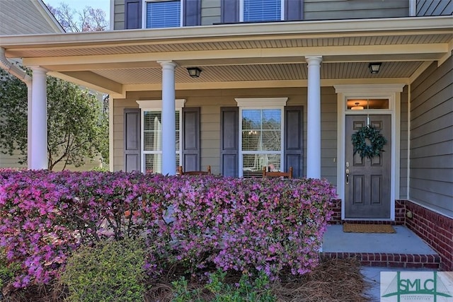 doorway to property featuring brick siding and covered porch