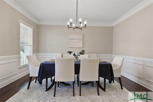 dining room with wainscoting, an inviting chandelier, wood finished floors, and crown molding