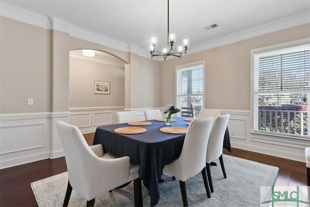 dining space with wood finished floors, visible vents, arched walkways, ornamental molding, and a chandelier