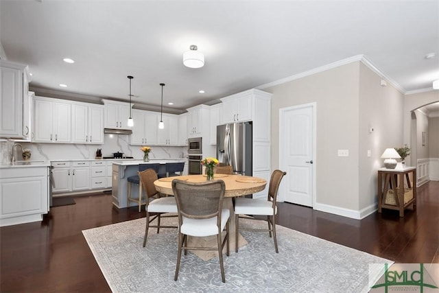 dining room featuring dark wood-style floors, recessed lighting, arched walkways, crown molding, and baseboards