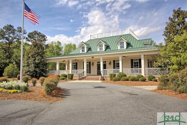 farmhouse featuring stucco siding, a ceiling fan, a standing seam roof, covered porch, and metal roof