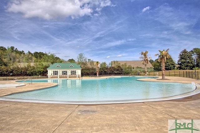 community pool with a patio, an outdoor structure, and fence