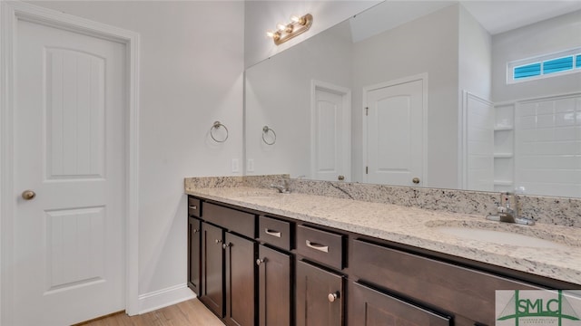 full bathroom with double vanity, wood finished floors, baseboards, and a sink