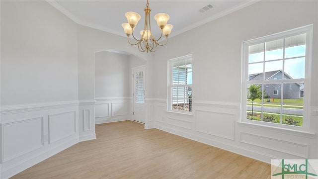 unfurnished dining area with visible vents, arched walkways, ornamental molding, a notable chandelier, and light wood-type flooring