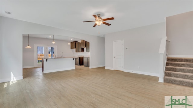 unfurnished living room featuring visible vents, baseboards, light wood-style flooring, and stairway