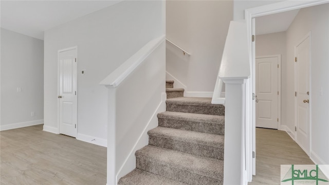 staircase featuring baseboards and wood finished floors