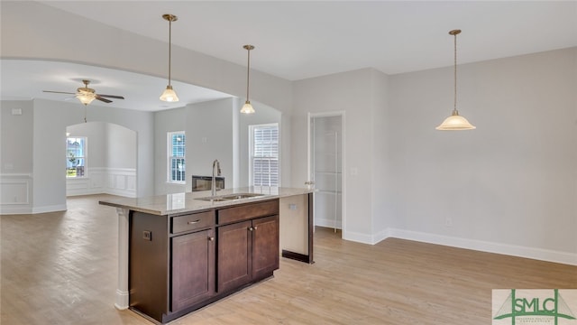 kitchen with open floor plan, pendant lighting, arched walkways, and a sink