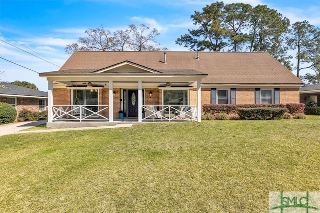 view of front facade featuring a ceiling fan, covered porch, a shingled roof, a front lawn, and brick siding