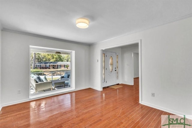 spare room with baseboards, wood finished floors, and crown molding