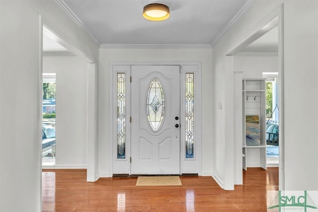 entrance foyer featuring baseboards, wood finished floors, and crown molding