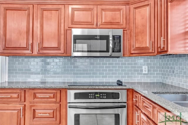 kitchen featuring stainless steel appliances, light stone countertops, and tasteful backsplash