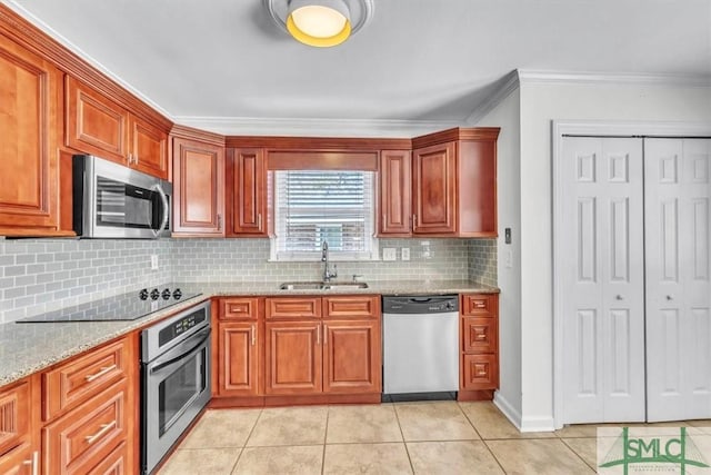 kitchen featuring crown molding, light stone countertops, light tile patterned floors, stainless steel appliances, and a sink