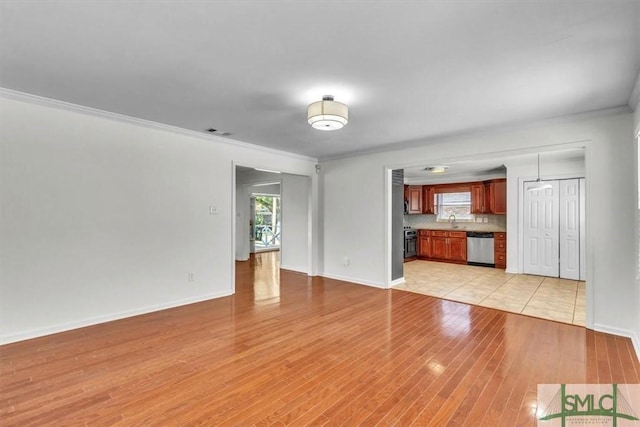 unfurnished living room featuring a sink, light wood-type flooring, baseboards, and ornamental molding