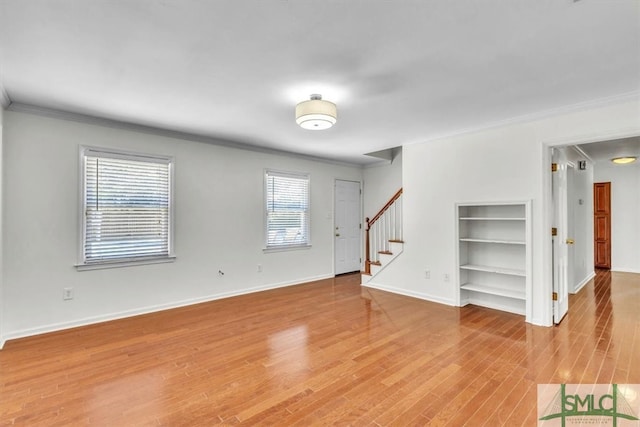 interior space featuring stairway, baseboards, ornamental molding, and light wood finished floors