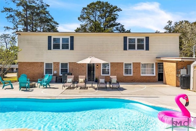 rear view of property with a patio area, fence, an outdoor pool, and brick siding