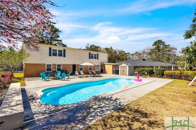 outdoor pool with a patio, an outbuilding, a lawn, and a shed