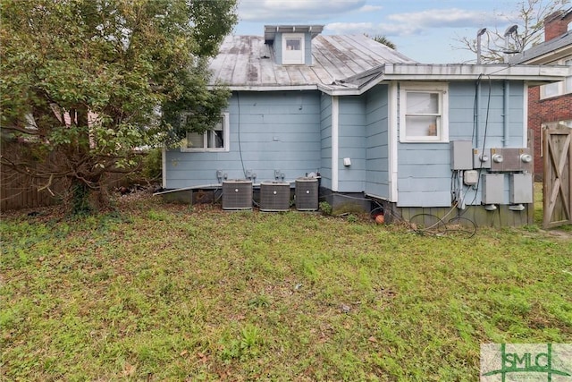 rear view of property featuring cooling unit and a yard