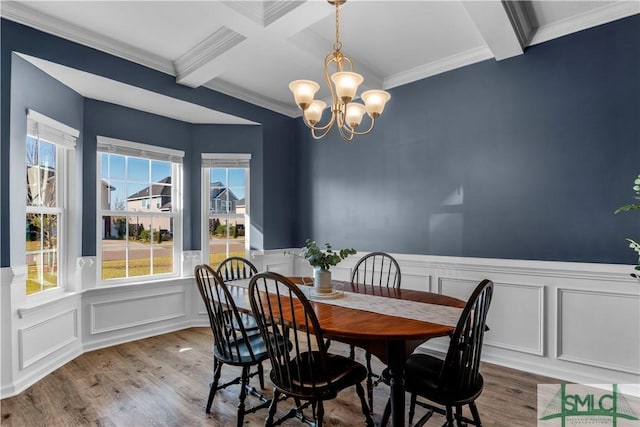 dining room with a wainscoted wall, beam ceiling, a notable chandelier, and wood finished floors