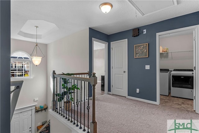 corridor with carpet, attic access, a tray ceiling, an upstairs landing, and independent washer and dryer