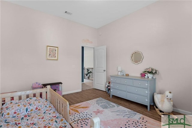 bedroom featuring visible vents, baseboards, and wood finished floors