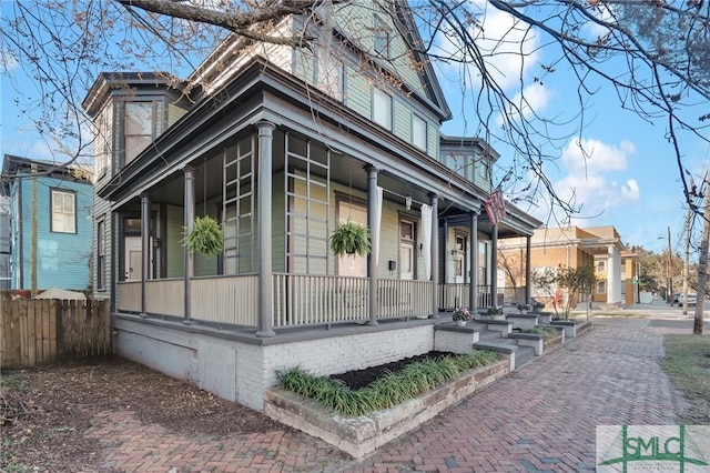 view of property exterior with covered porch and fence