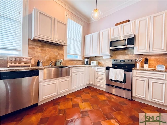 kitchen with backsplash, ornamental molding, stainless steel appliances, white cabinetry, and a sink