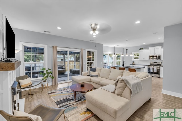 living room with recessed lighting, visible vents, baseboards, and light wood-style floors