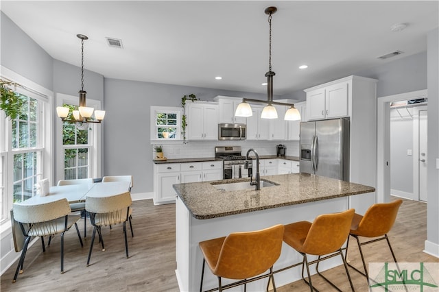 kitchen with a sink, decorative backsplash, visible vents, and stainless steel appliances