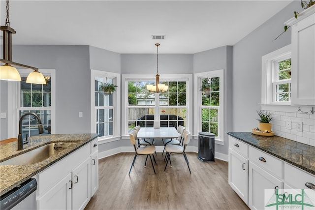 dining space with visible vents, plenty of natural light, light wood-type flooring, and an inviting chandelier