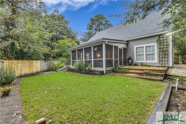 rear view of house with a lawn, a fenced backyard, and a sunroom