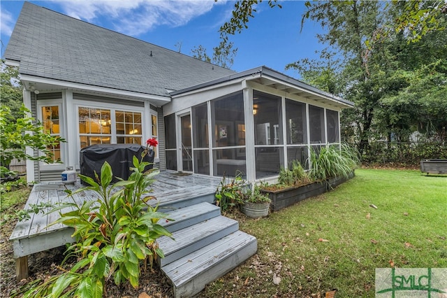 rear view of property featuring a yard, fence, a sunroom, and roof with shingles