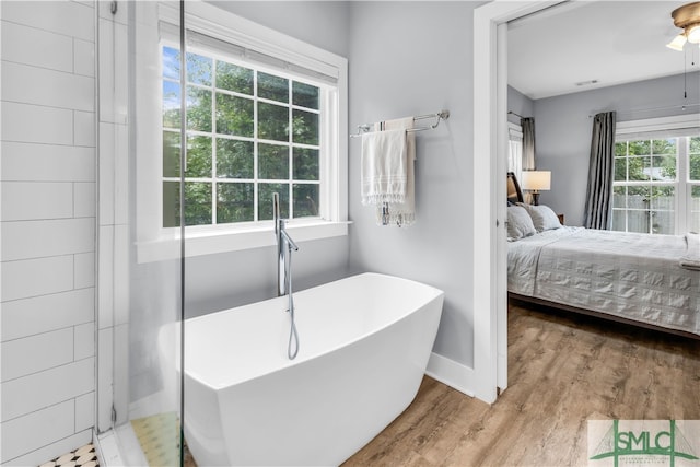 ensuite bathroom featuring a ceiling fan, wood finished floors, visible vents, a freestanding tub, and ensuite bathroom