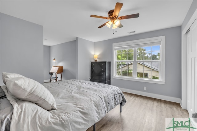 bedroom featuring light wood-type flooring, visible vents, baseboards, and ceiling fan