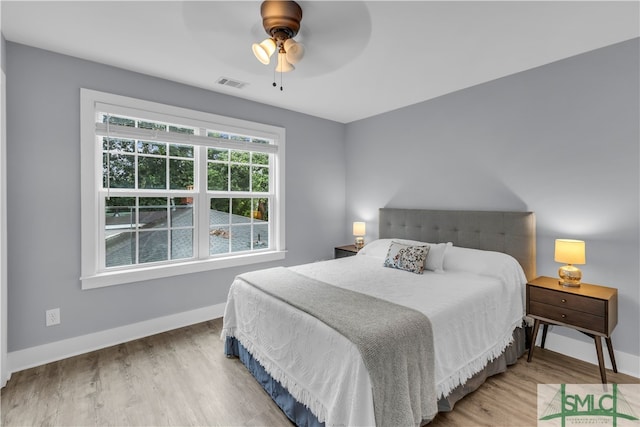 bedroom featuring ceiling fan, wood finished floors, visible vents, and baseboards