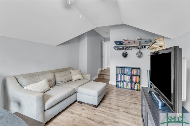 living room featuring vaulted ceiling, baseboards, and light wood-type flooring