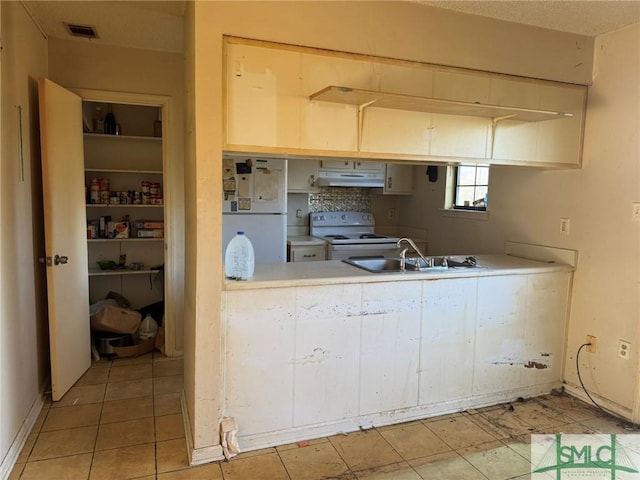 kitchen featuring visible vents, under cabinet range hood, a sink, white appliances, and light countertops