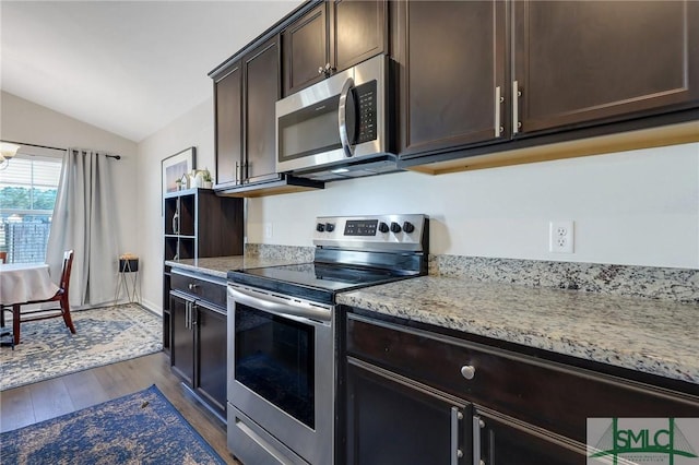 kitchen with light stone countertops, dark wood-style flooring, stainless steel appliances, vaulted ceiling, and dark brown cabinetry