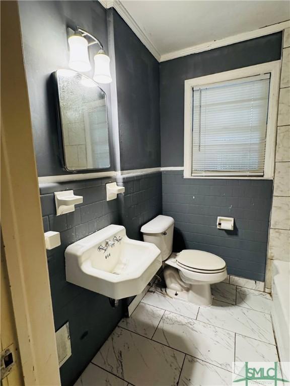 bathroom with toilet, ornamental molding, a bathtub, marble finish floor, and a sink