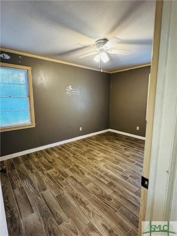 spare room with baseboards, wood finished floors, a ceiling fan, and crown molding