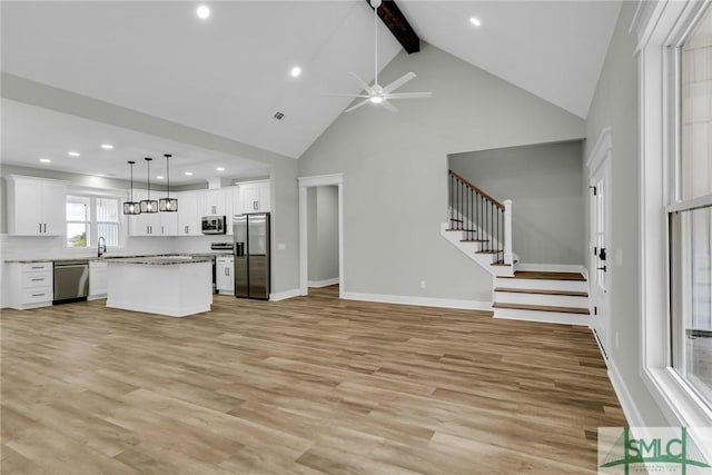 kitchen featuring open floor plan, appliances with stainless steel finishes, a ceiling fan, and a sink