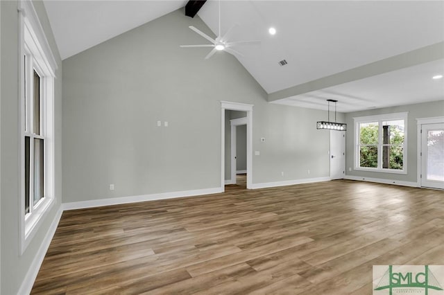 unfurnished living room featuring a ceiling fan, beamed ceiling, wood finished floors, and baseboards