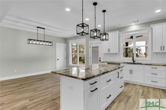 kitchen featuring a sink, plenty of natural light, a kitchen island, and light wood-style flooring