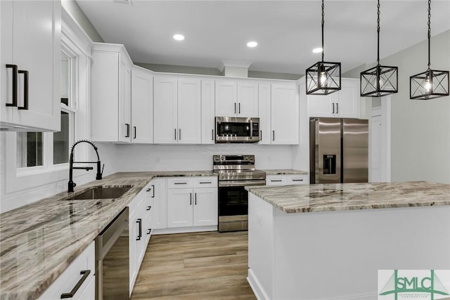 kitchen with a sink, white cabinets, light stone countertops, and stainless steel appliances