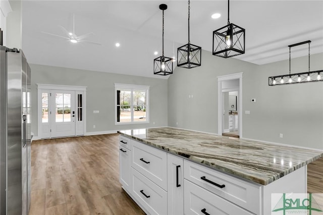 kitchen featuring a ceiling fan, light stone countertops, light wood-style floors, stainless steel refrigerator with ice dispenser, and open floor plan