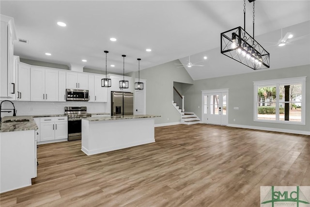 kitchen with a center island, stainless steel appliances, ceiling fan, and a sink