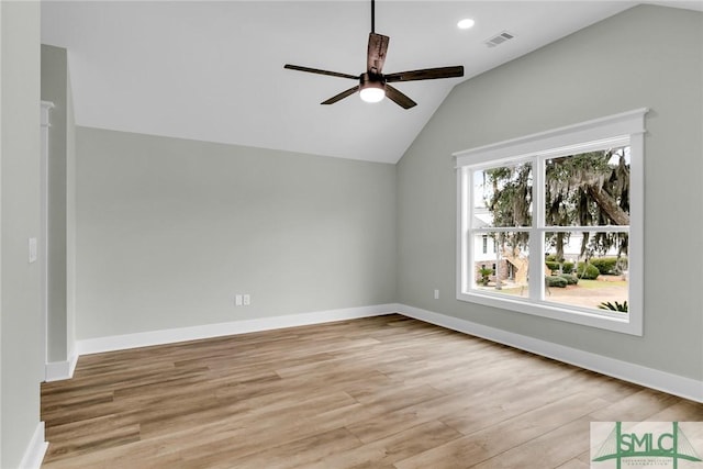 empty room featuring vaulted ceiling, a ceiling fan, visible vents, and light wood-type flooring