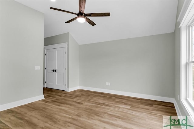 interior space with baseboards, light wood-style floors, ceiling fan, and vaulted ceiling