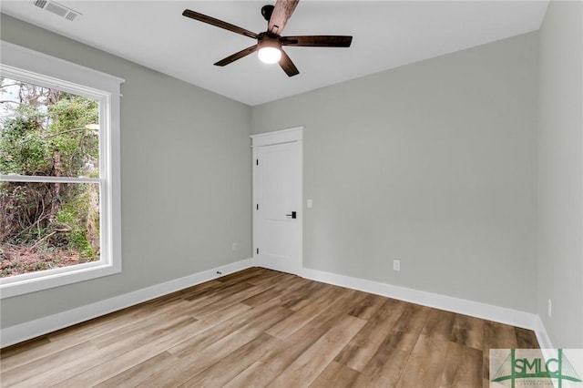 spare room featuring a wealth of natural light, visible vents, baseboards, and wood finished floors